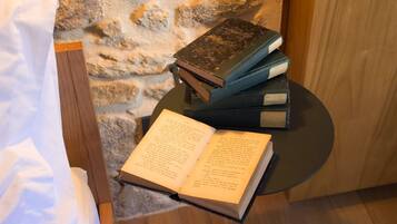 A stack of books on a small round table, with an open book in front of it.