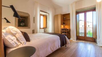Een slaapkamer met een bed, een bureau en een balkon.