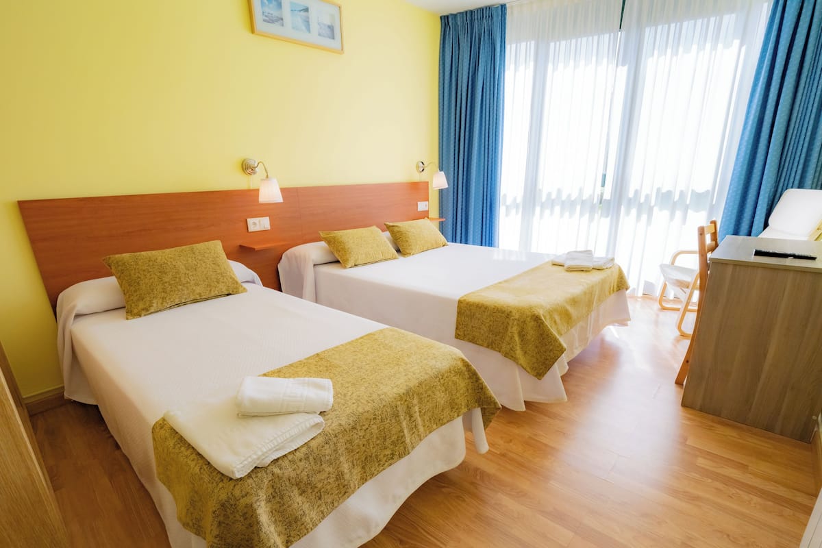 Une chambre d’hôtel avec deux lits, des têtes de lit en bois, un bureau et une chaise.