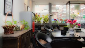 A restaurant interior with a counter, seating area, and potted plants. - Hotel Ciudad de Alcalá (Alcala de Henares)