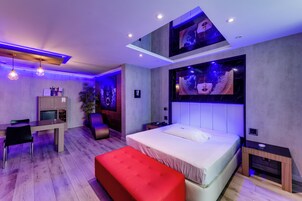 Un dormitorio moderno con cama, escritorio y un reposapiés rojo.