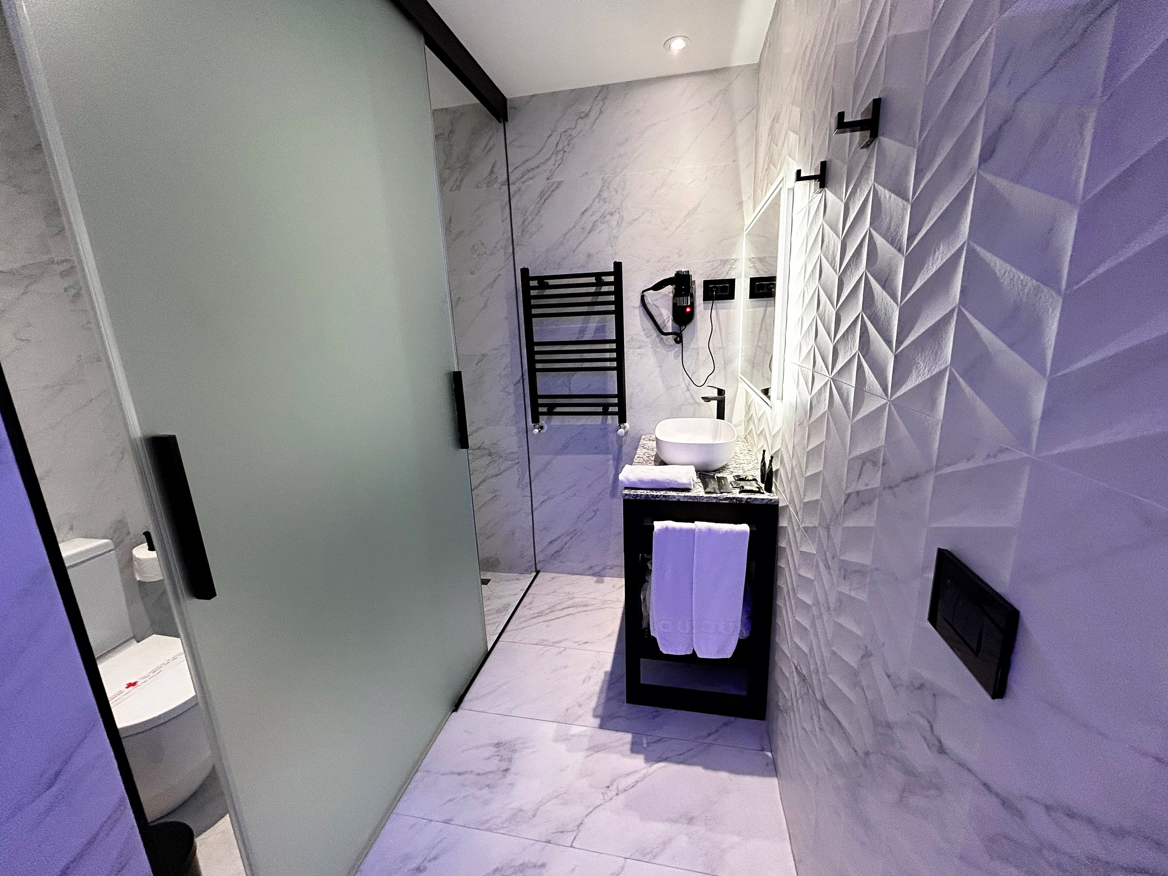A modern bathroom with a marble floor, a large sink, and a towel rack.