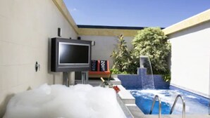 Un área de piscina con jacuzzi, un televisor montado en la pared y un letrero que dice "HOT".