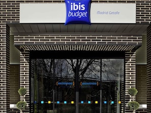 The exterior of a Madrid Getafe ibis budget hotel with a clear entrance and a signboard above the door. - Ibis Budget Madrid Getafe (Getafe)