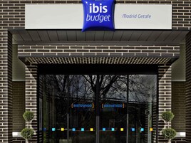Exterior de un hotel ibis budget Madrid Getafe, con entrada despejada y un cartel sobre la puerta.