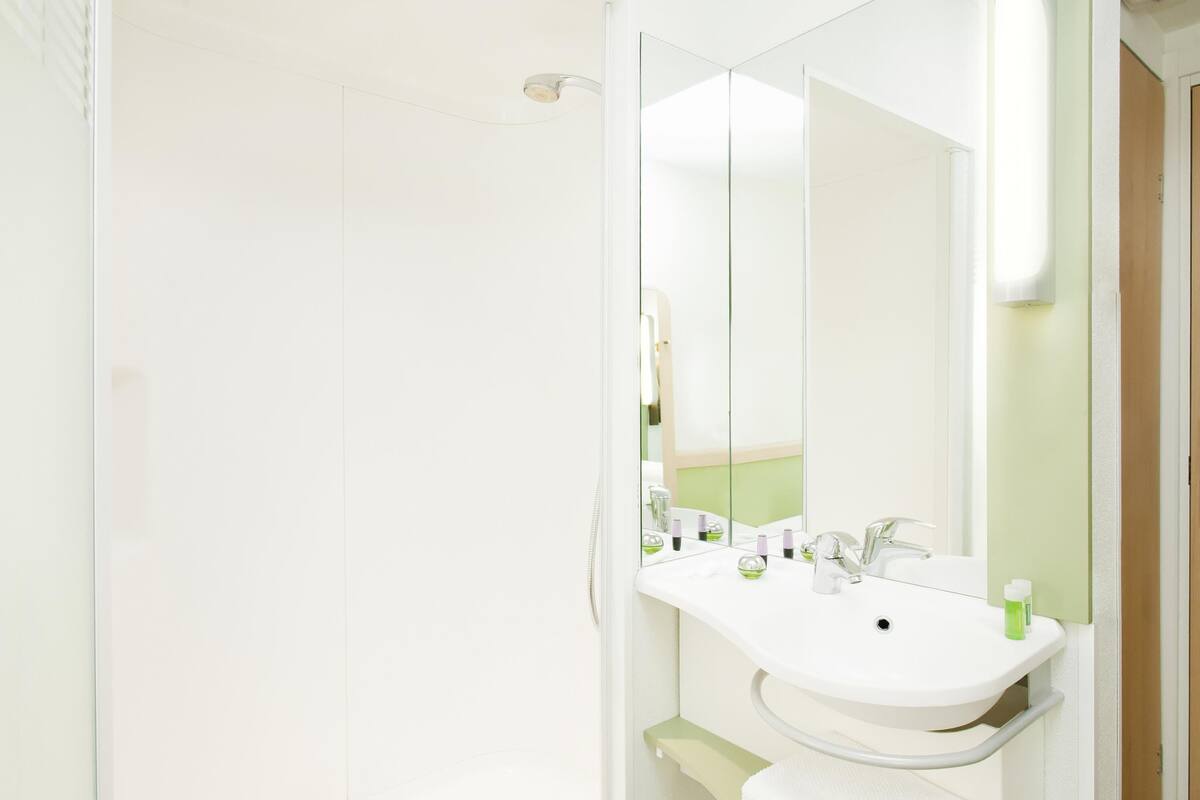 A bathroom with a white sink, mirror, and shower.