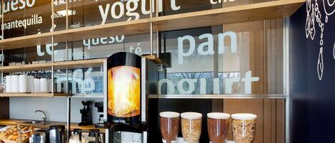 A café interior with a coffee machine, sugar dispensers, and a display of pastries.