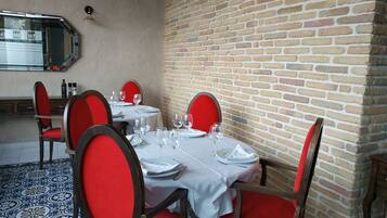 A dining area with a brick wall, red chairs, and a tiled floor.