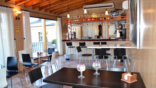 A restaurant with a bar area, wooden ceiling, and a view of the outside. - Hotel Venta el Puerto (Murcia)