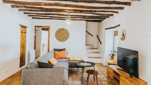 Una sala de estar con un sofá, un televisor, una escalera y techo de madera.