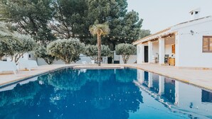 A swimming pool with clear blue water, surrounded by white lounge chairs and trees. - Casa Pedro Barrera (Caravaca de la Cruz)