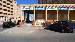 A building with multiple 'La Manga' signs, a 'Hawai'i 6' sign, and a residential area. - Hawaii 6 (La Manga)