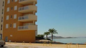 A multi-story hotel with balconies, located near a beach with palm trees and a view of the sea. - Vistamar (San Javier)