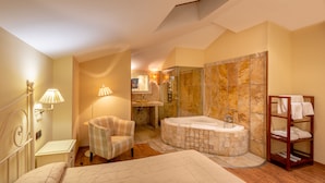 Un dormitorio amplio con una cama grande, una zona de estar, un vestidor y un baño con bañera y ducha.