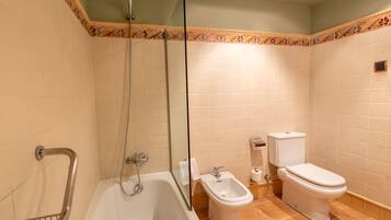 A bathroom with a bathtub, a bidet, and a toilet.