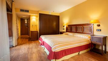 Une chambre d’hôtel avec un grand lit, une tête de lit en bois, deux lampes de chevet, une table de chevet et une armoire.