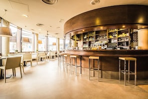 Un espace bar moderne avec un comptoir incurvé, des tabourets de bar et un intérieur bien éclairé.