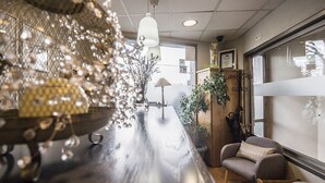 A bar area with a long counter, hanging lights, and a potted plant. There is a seating area with chairs and a table. - Casa Jacinto Pamplona  (Burlada)
