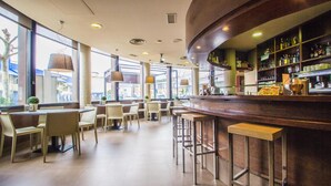 A modern bar area with a curved counter, bar stools, and a view of the street through large windows. - Casa Jacinto Pamplona  (Burlada)
