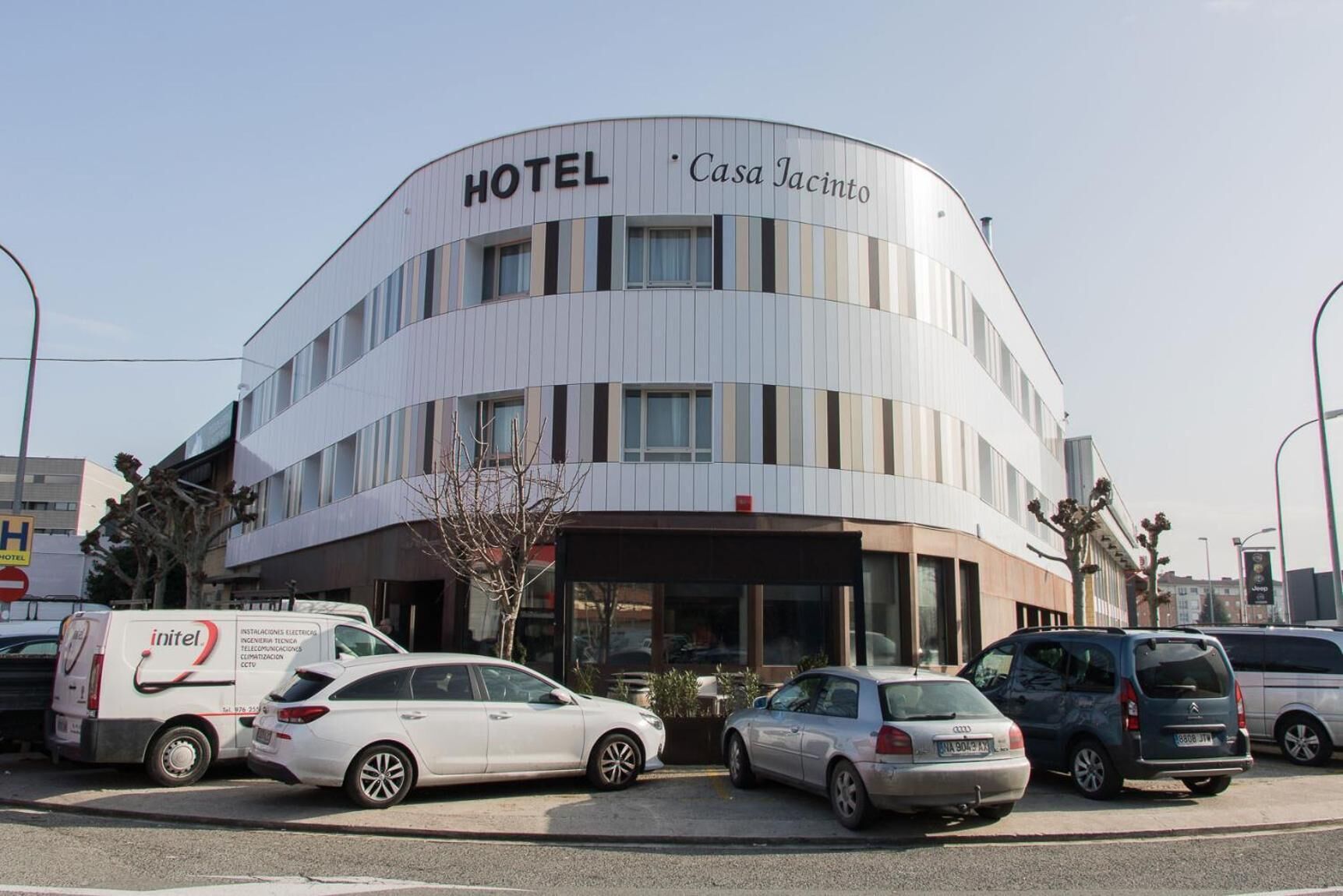 Een modern hotel met een gebogen gevel, veel ramen, en een bord met de tekst 'HOTEL Casa Jacinto'.