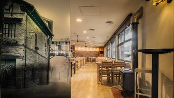 A restaurant with a stone facade, wooden tables, and a view through large windows.