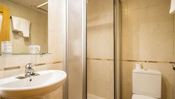 Een badkamer met een douche met glazen wand, een wastafel en een toilet.