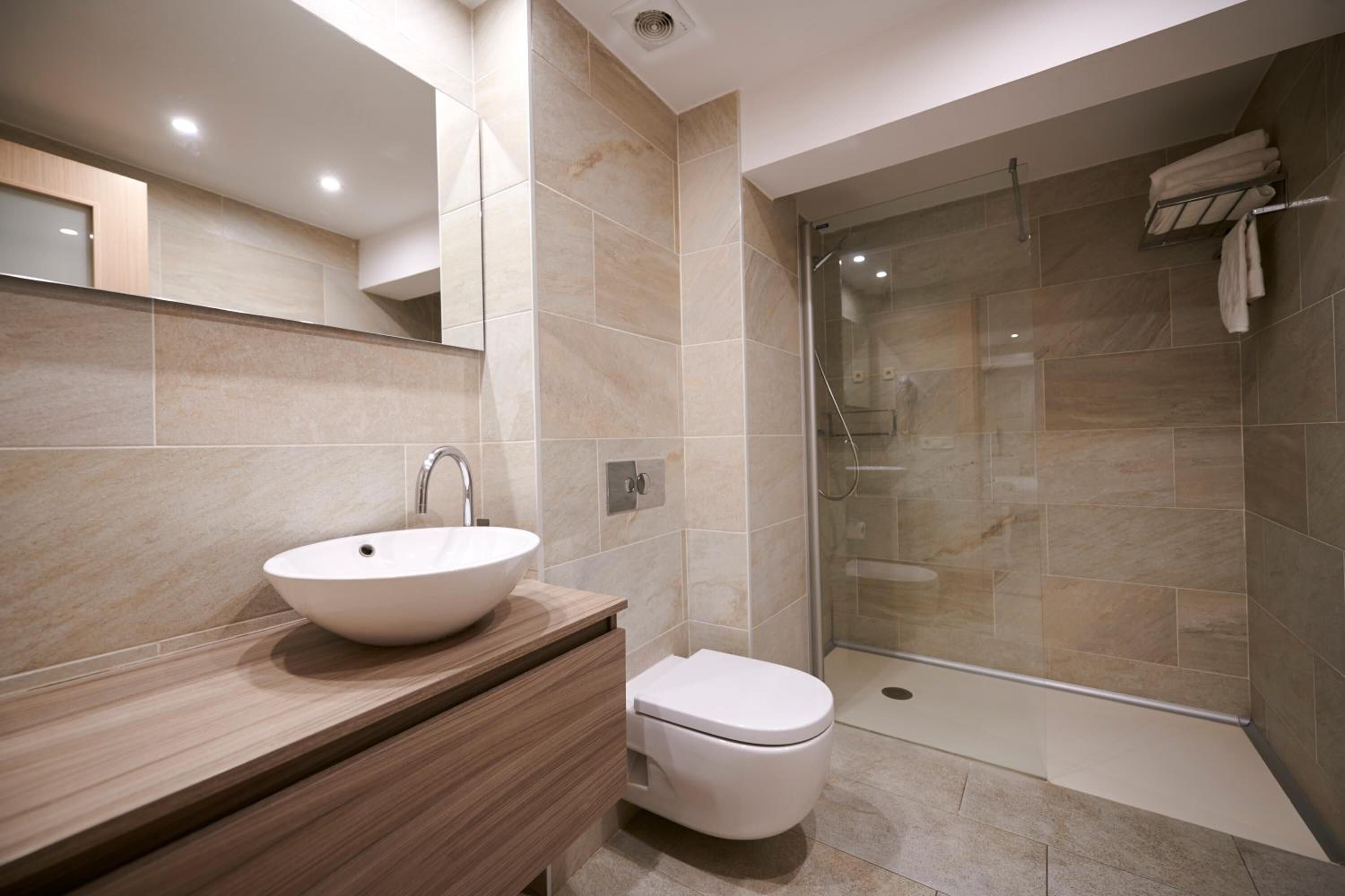 A modern bathroom with a large sink, toilet, and glass shower enclosure.