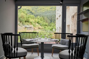A dining area with a round table and four chairs, a window with a view of a green landscape.