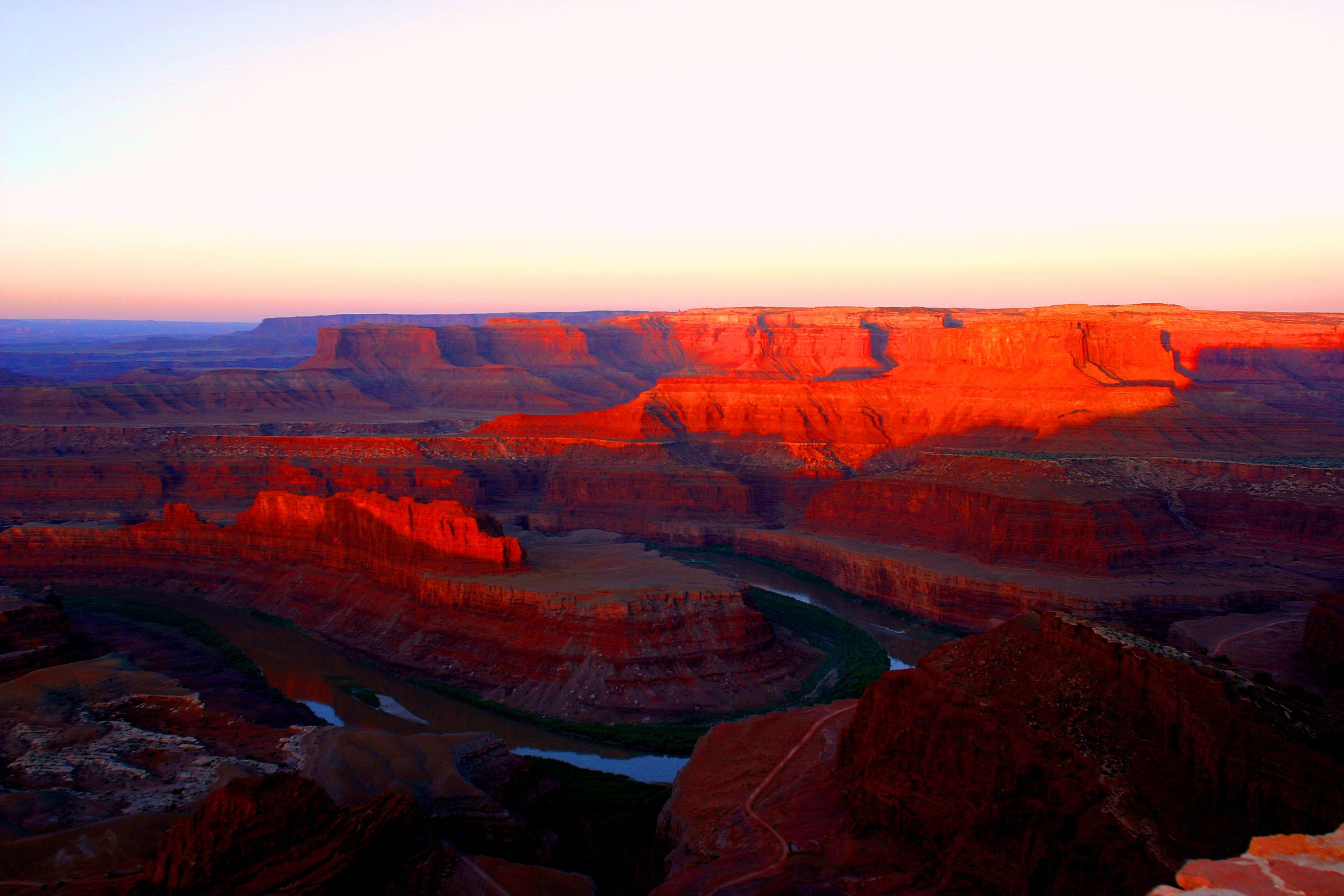 Een canyonlandschap met gelaagde rotsformaties en een rivier.