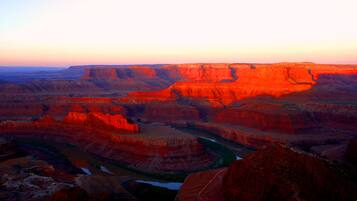 Een canyonlandschap met gelaagde rotsformaties en een rivier.
