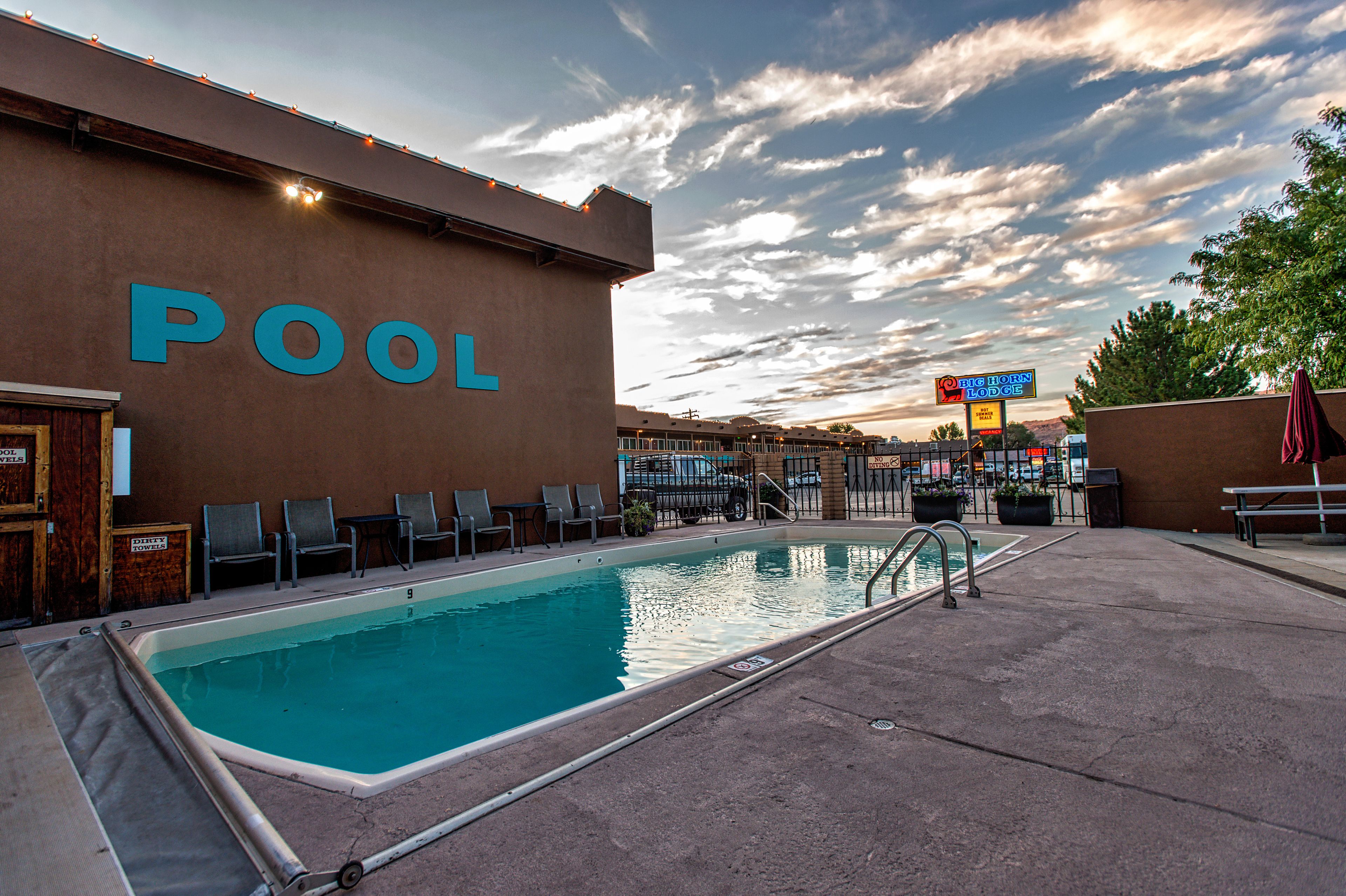 A pool area with lounge chairs and a sign for the pool.