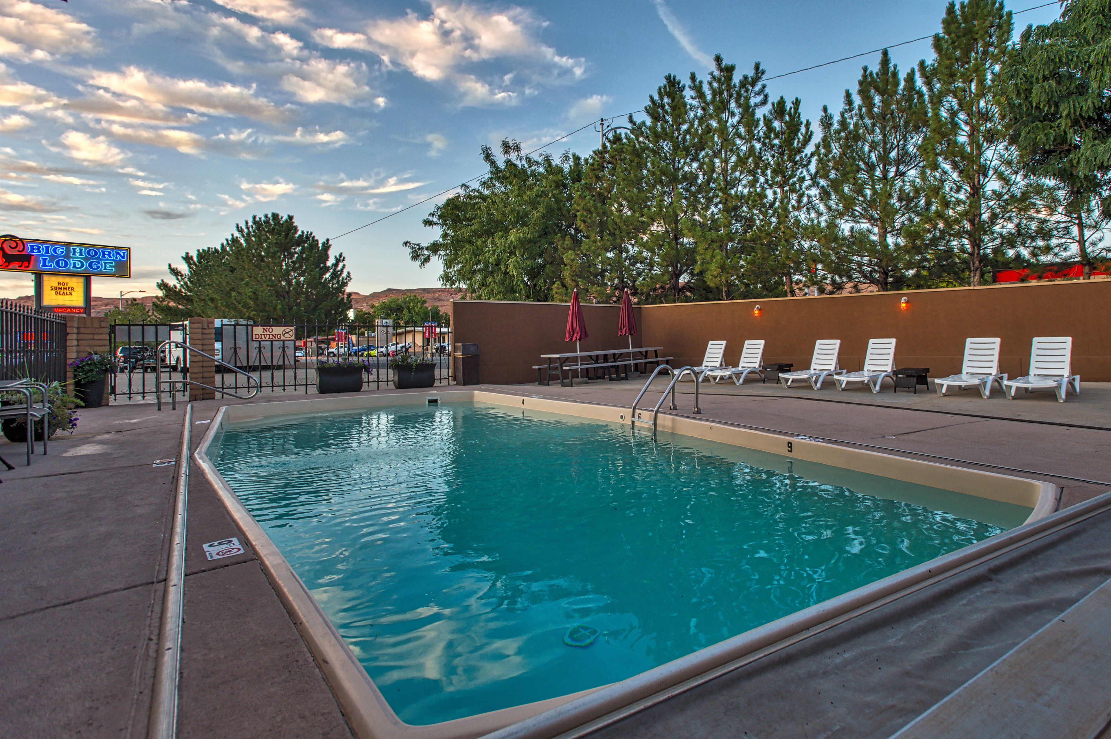 A swimming pool with lounge chairs and a sign for Big Horn Lodge.