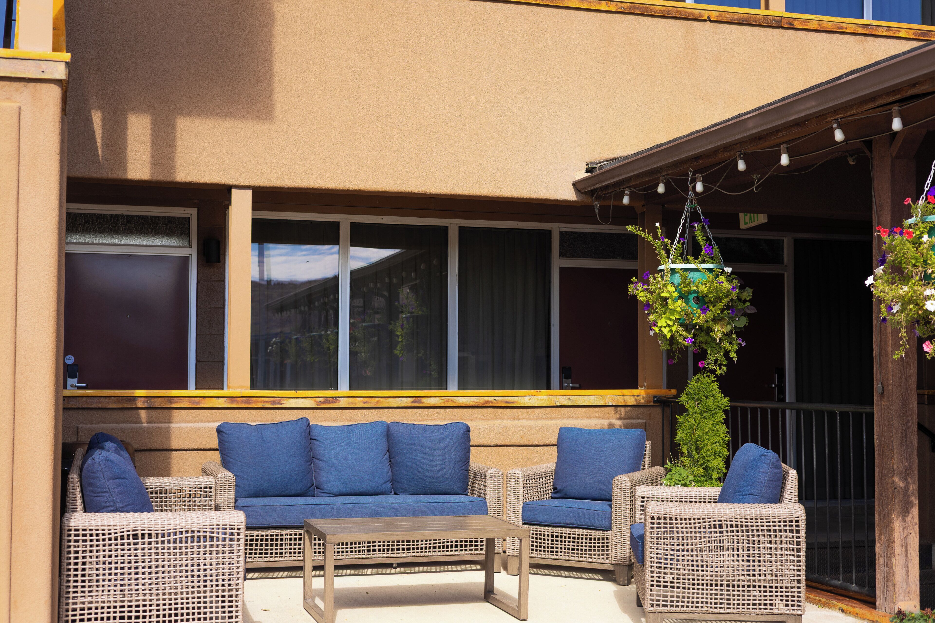 An outdoor seating area with wicker furniture and a hanging flower planter.