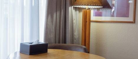Habitación de hotel con una mesa redonda de madera, una caja de pañuelos, una lámpara y un cuadro en la pared.