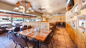 A restaurant with wooden paneling, multiple dining tables, and ceiling fans.