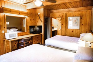 A wooden cabin room with two beds, a desk with a television, a microwave, and a chair. - Big Horn Lodge, a Dazzler Select by Wyndham (Moab)