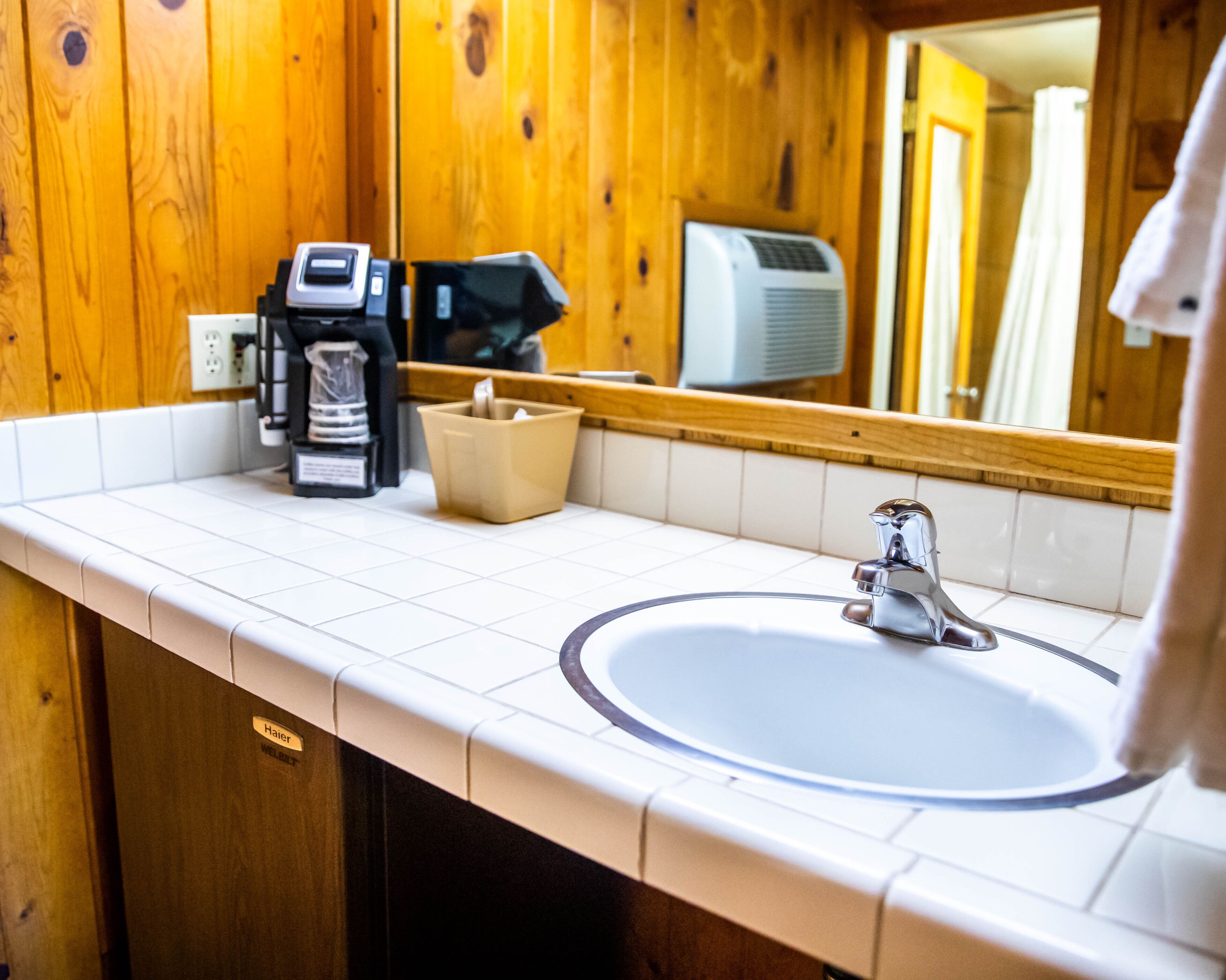 A bathroom with a white sink, a mirror, and wooden paneling.