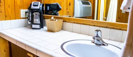A bathroom with a white sink, a mirror, and wooden paneling.