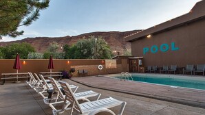 A pool area with lounge chairs, a sign indicating no diving, and a view of a mountain range.