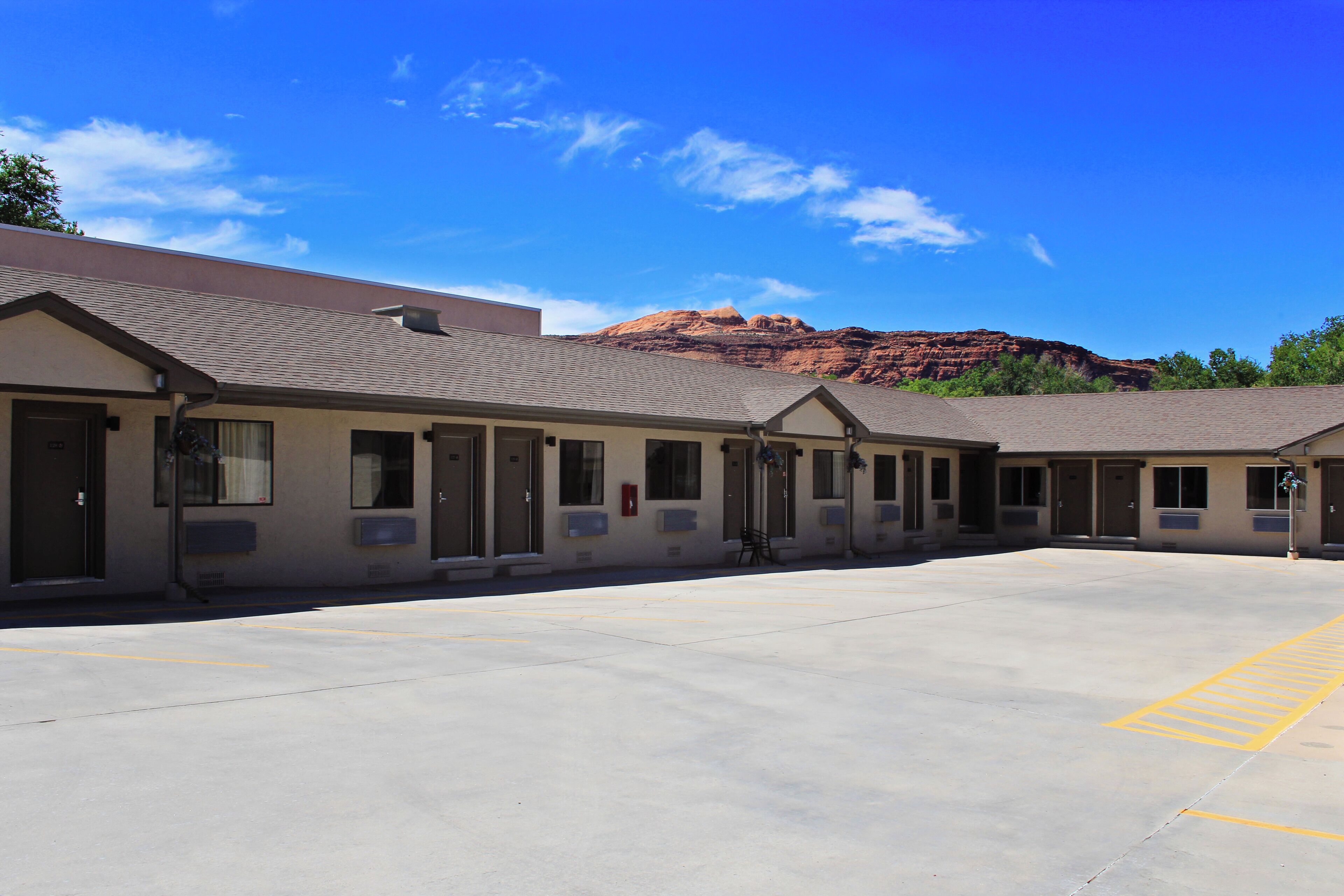 A motel with a parking lot and a mountain backdrop.