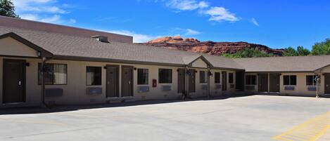 A motel with a parking lot and a mountain backdrop.