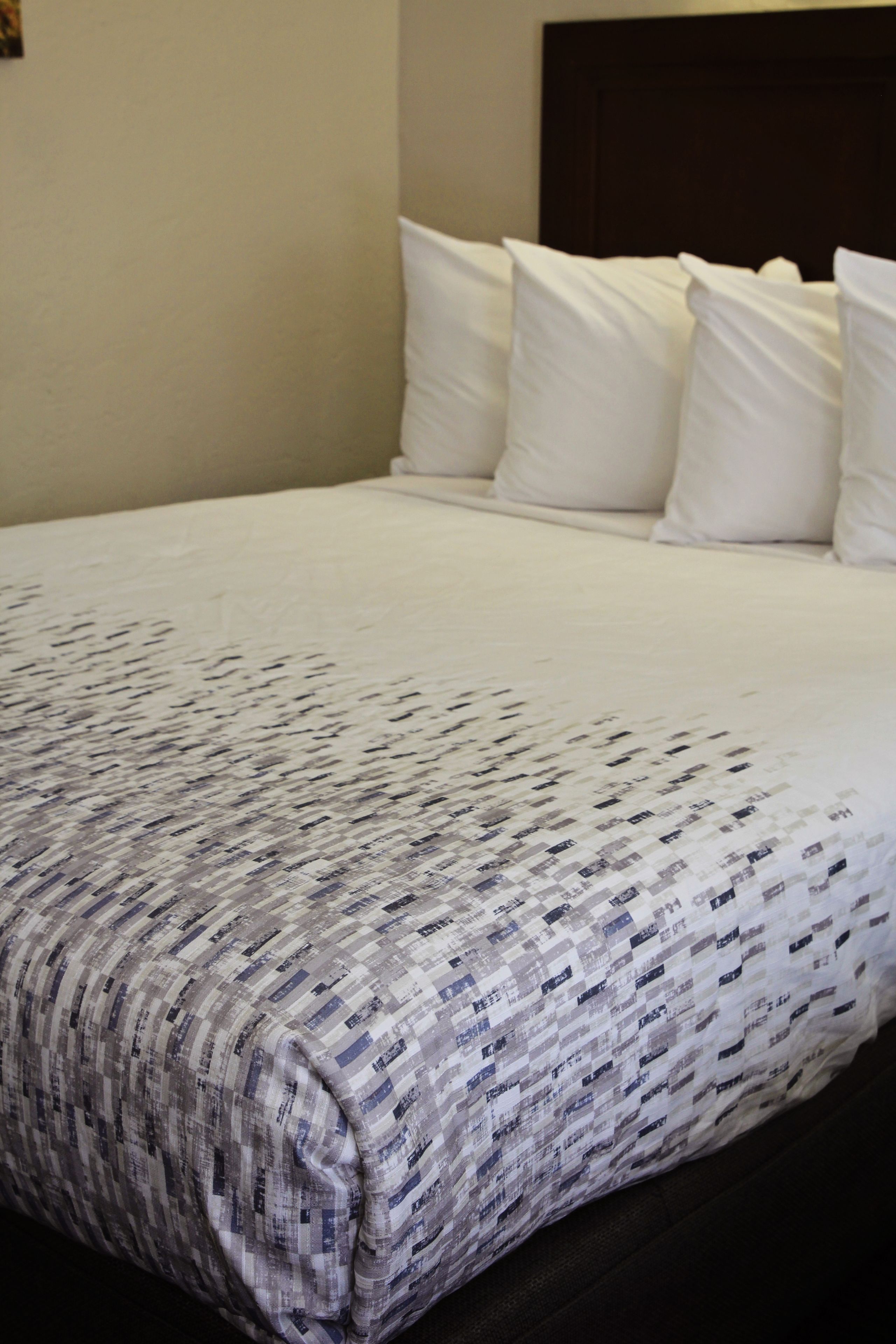Una cama bien hecha con una colcha estampada y almohadas blancas.