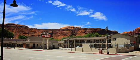 A hotel with a sign reading "BOWEN HOTEL" in a desert town with red rock formations in the background.