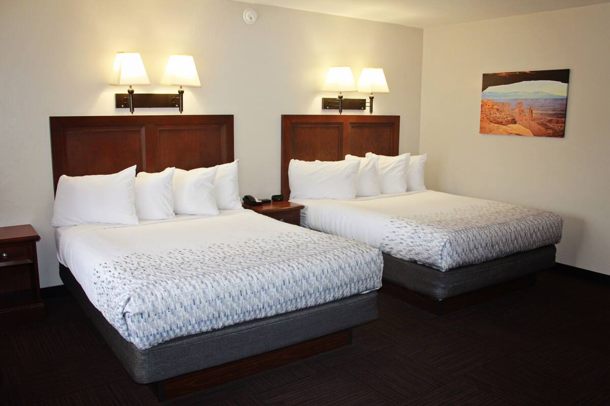 Two double beds with headboards, bedside lamps, a nightstand, and a painting on the wall.