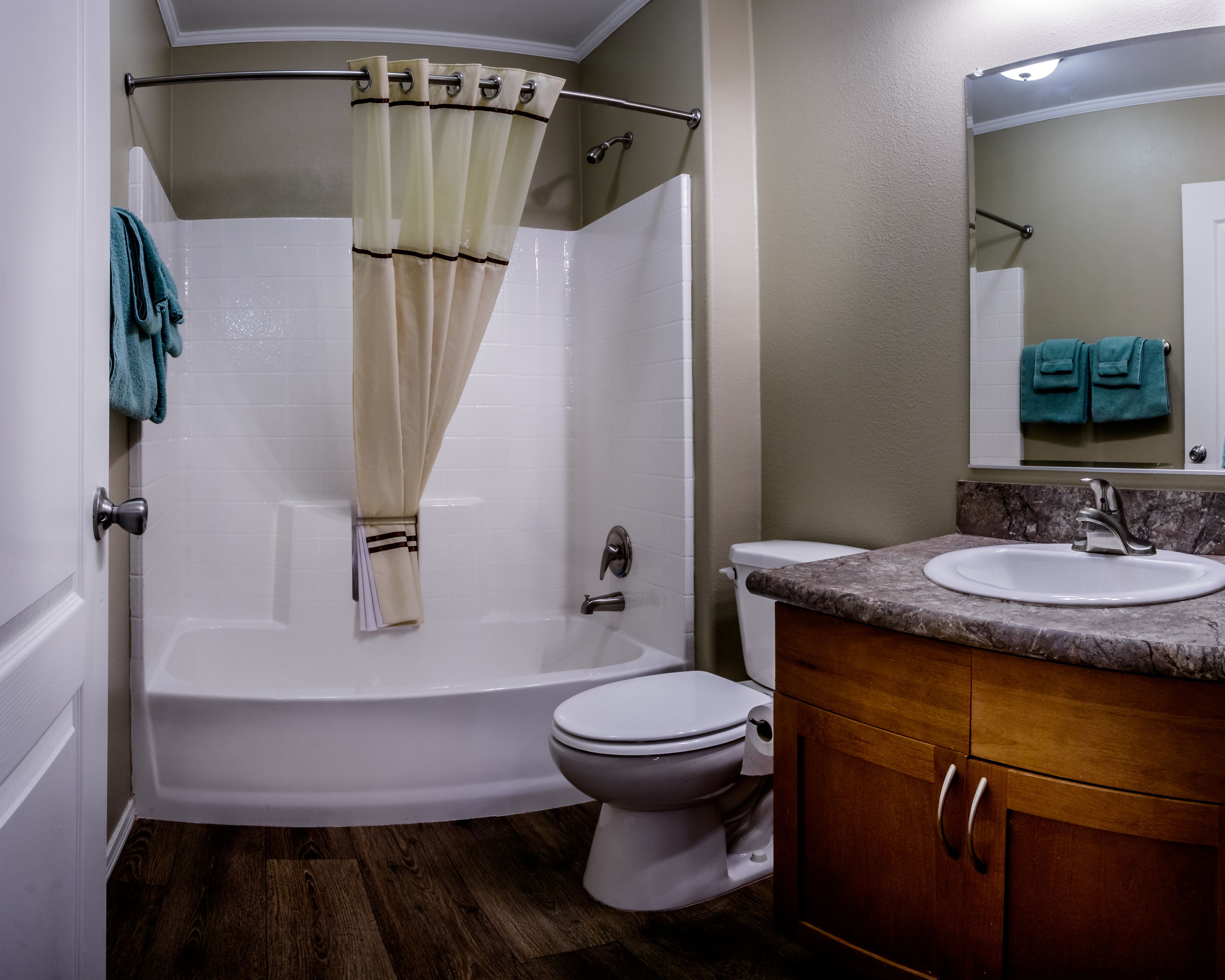 A bathroom with a bathtub, toilet, vanity, and a shower curtain.