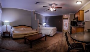 A compact living space with a sofa, a bed, a dining table, and a kitchenette.