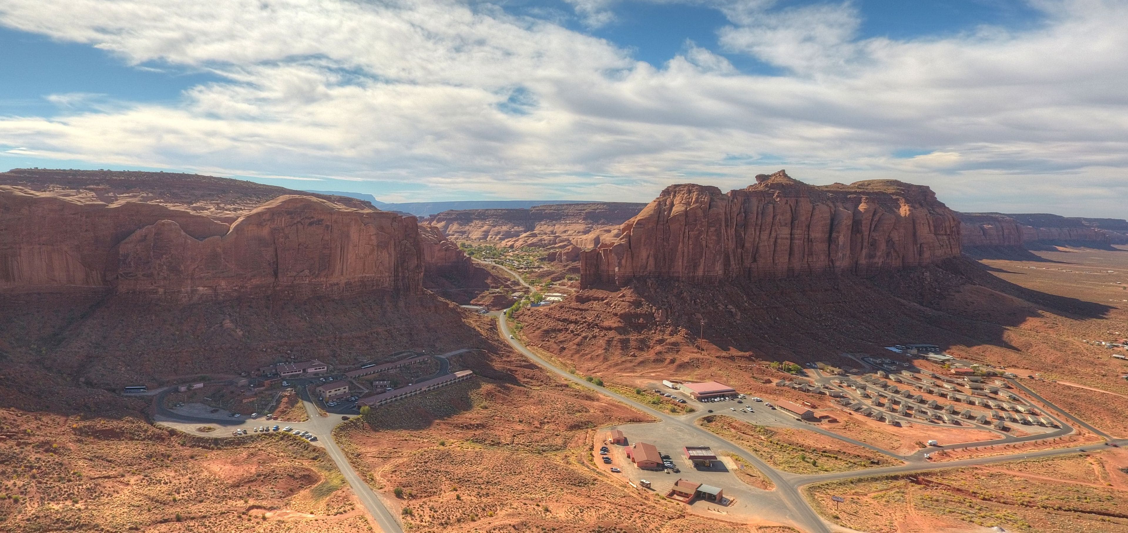 A desert landscape with a large building complex featuring multiple parking areas and a winding road.