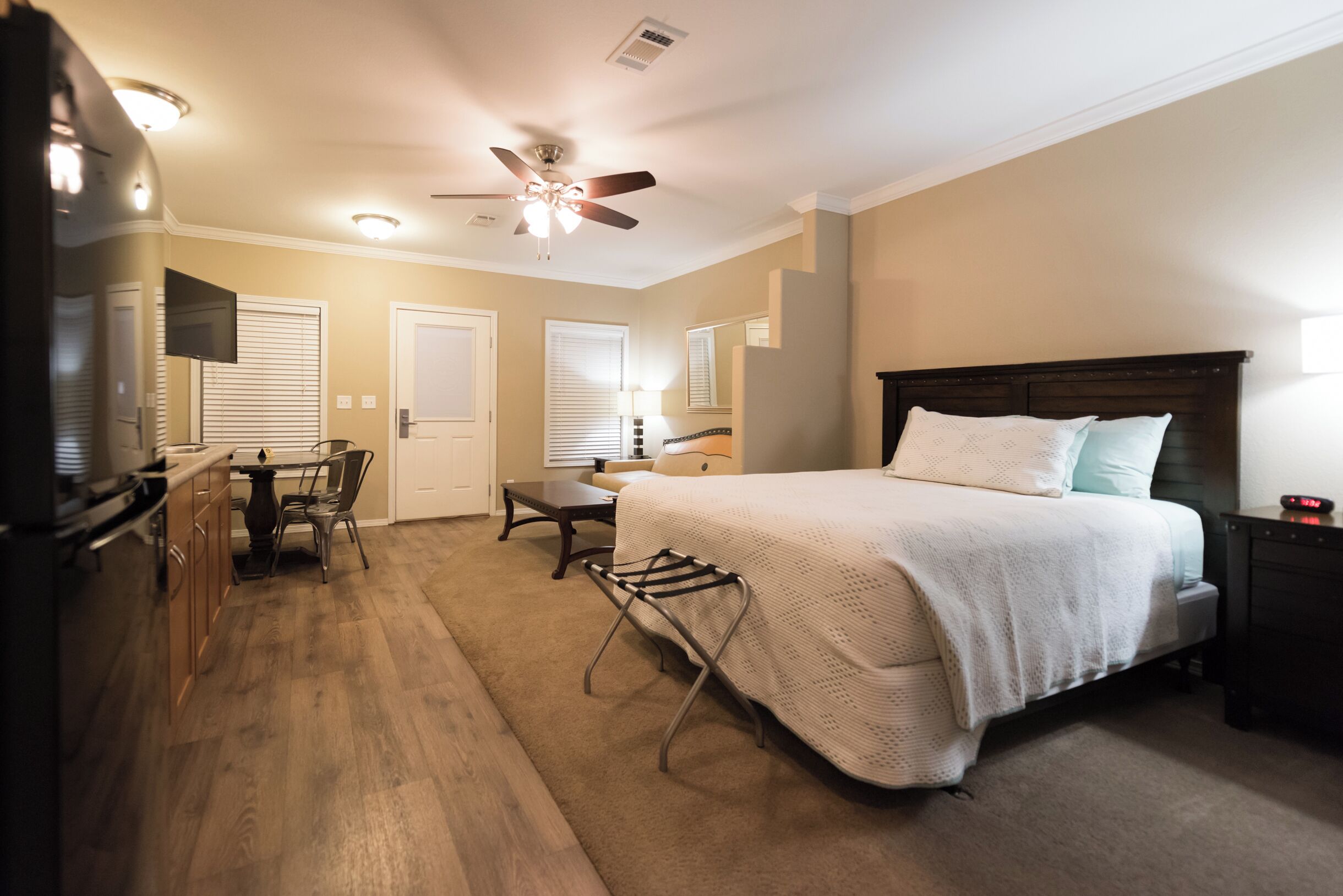 A bedroom with a bed, bedside table, lamp, and a ceiling fan.