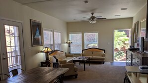 A spacious living room with a wooden dining table, two sofas, a coffee table, and a ceiling fan.
