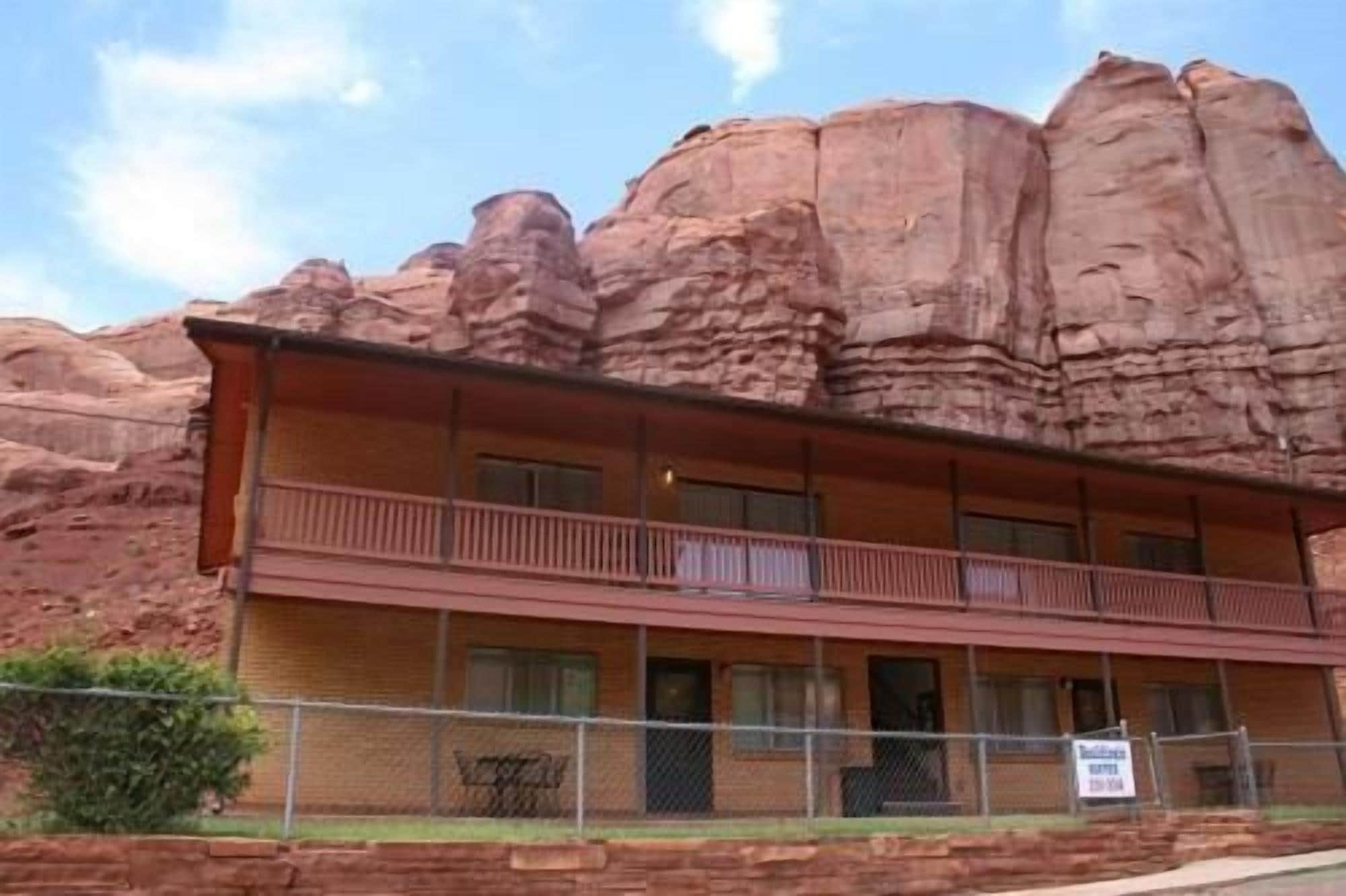 A two-story building with a balcony on the second floor, surrounded by red rock formations.